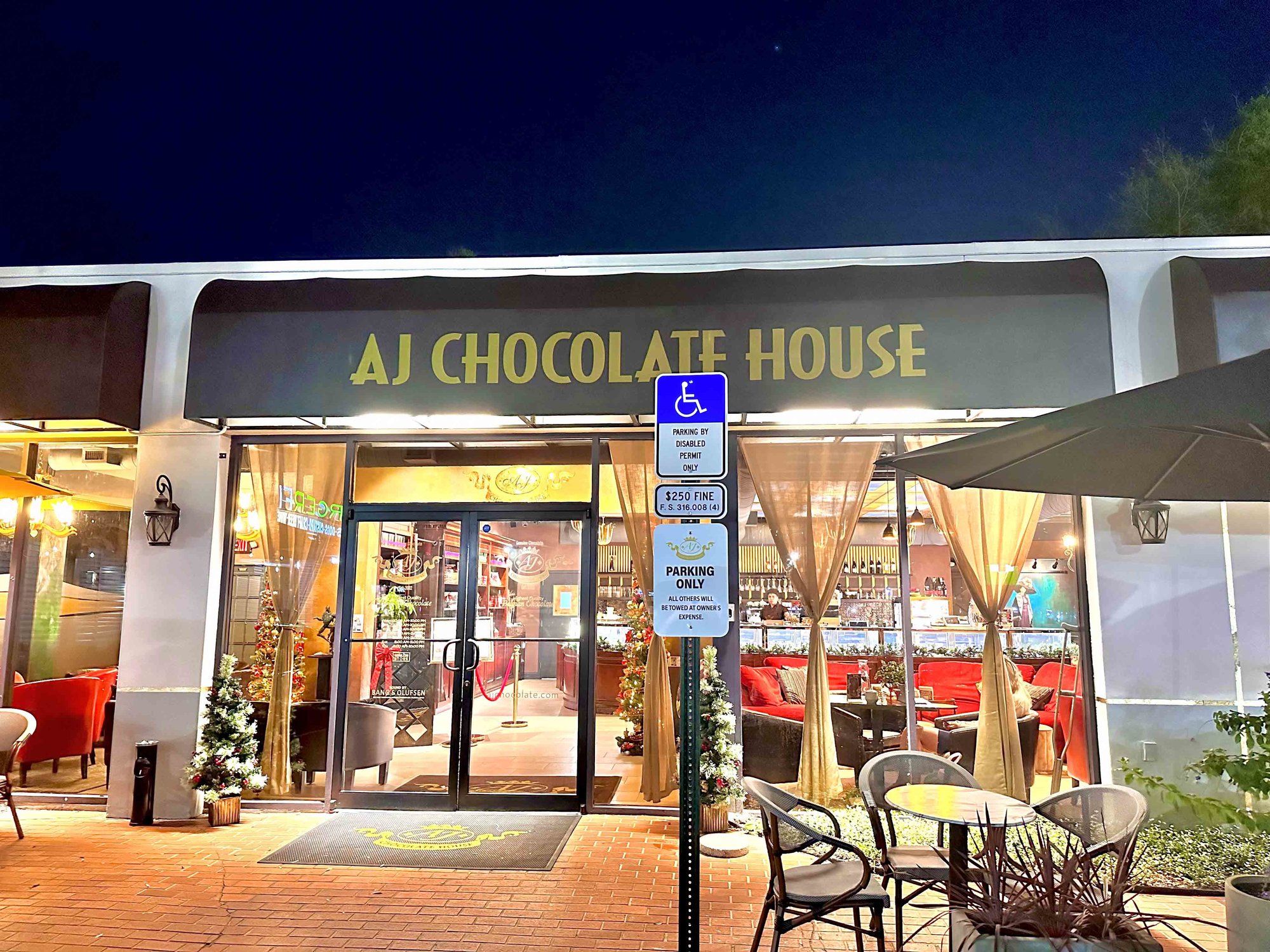 front of aj chocolate house with a brown sign and glass windows